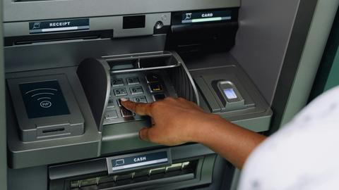A person enters their PIN number at an ATM