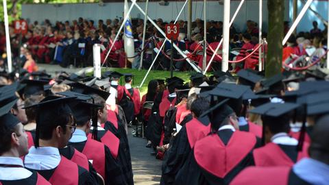 Harvard graduates seated in rows in Harvard Yard during commencement