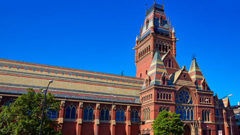 A gothic-style red brick building with tall arched windows, ornate architecture, and a tower in the middle