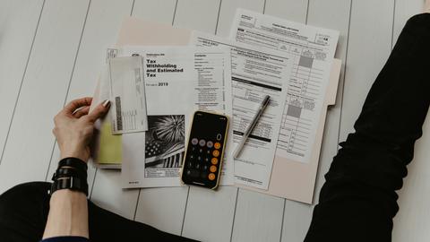 A person looks through a folder of tax forms spread out in front of them