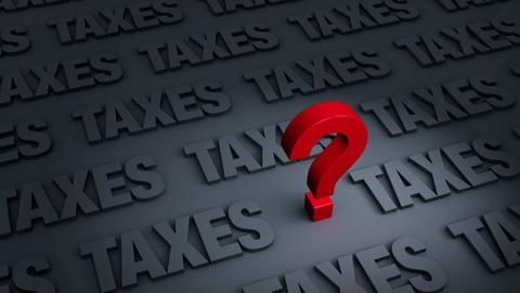 A red question mark standing on top of a gray background with the word "taxes" written across it