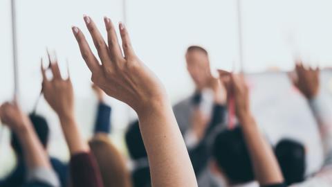 Students raise their hands to ask questions during a classroom discussion