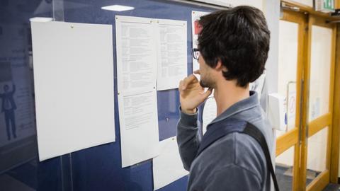A student looks at notices posted on a wall 