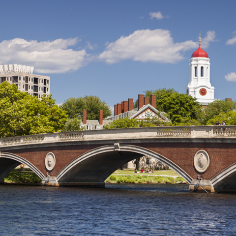 A foot bridge across the Charles River with buildings in the background