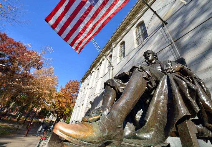 The John Harvard statue on a bright sunny day in Harvard Yard