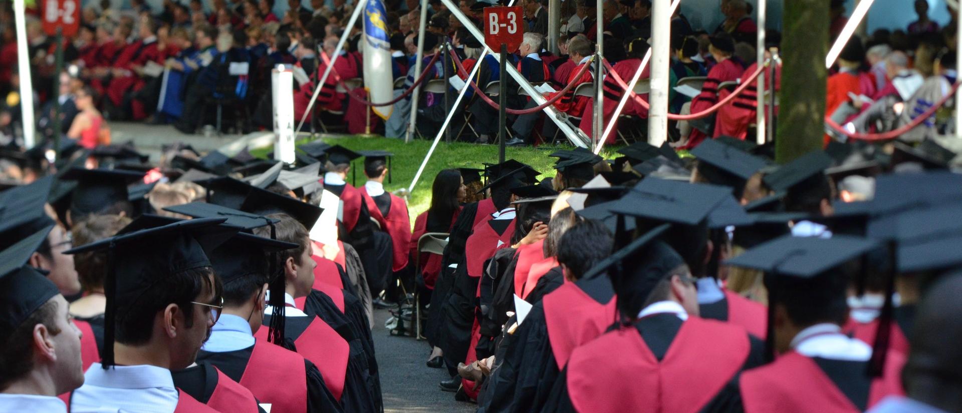 Harvard graduates seated in rows in Harvard Yard during commencement
