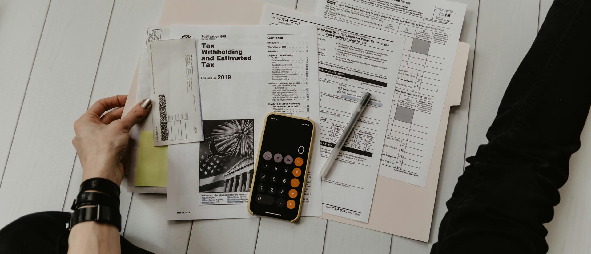 A person looks through a folder of tax forms spread out in front of them