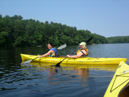 A host and student kayaking together